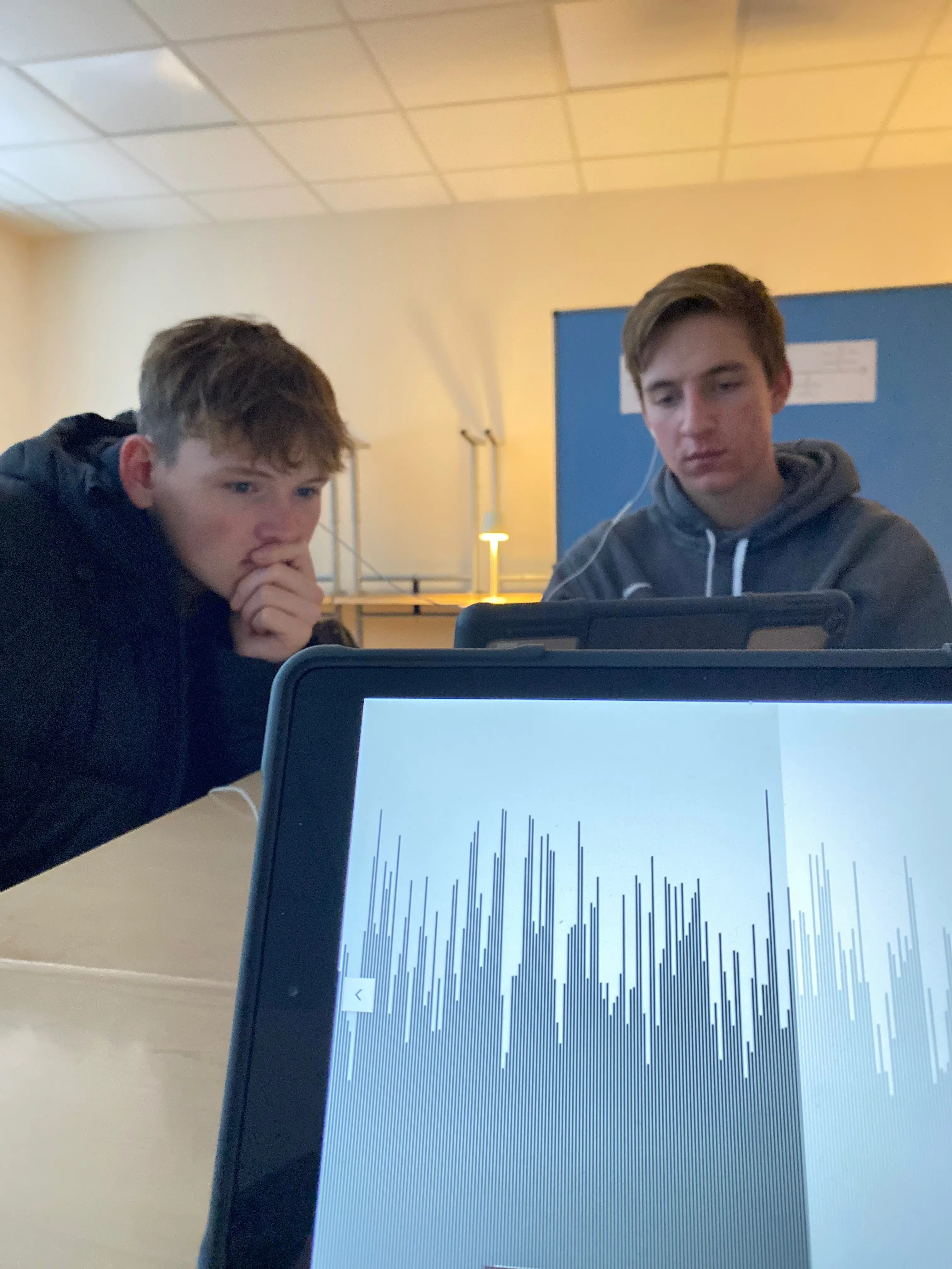 iPad mit Podcast, Schüler mit Kopfhöhrern im Hintergrund