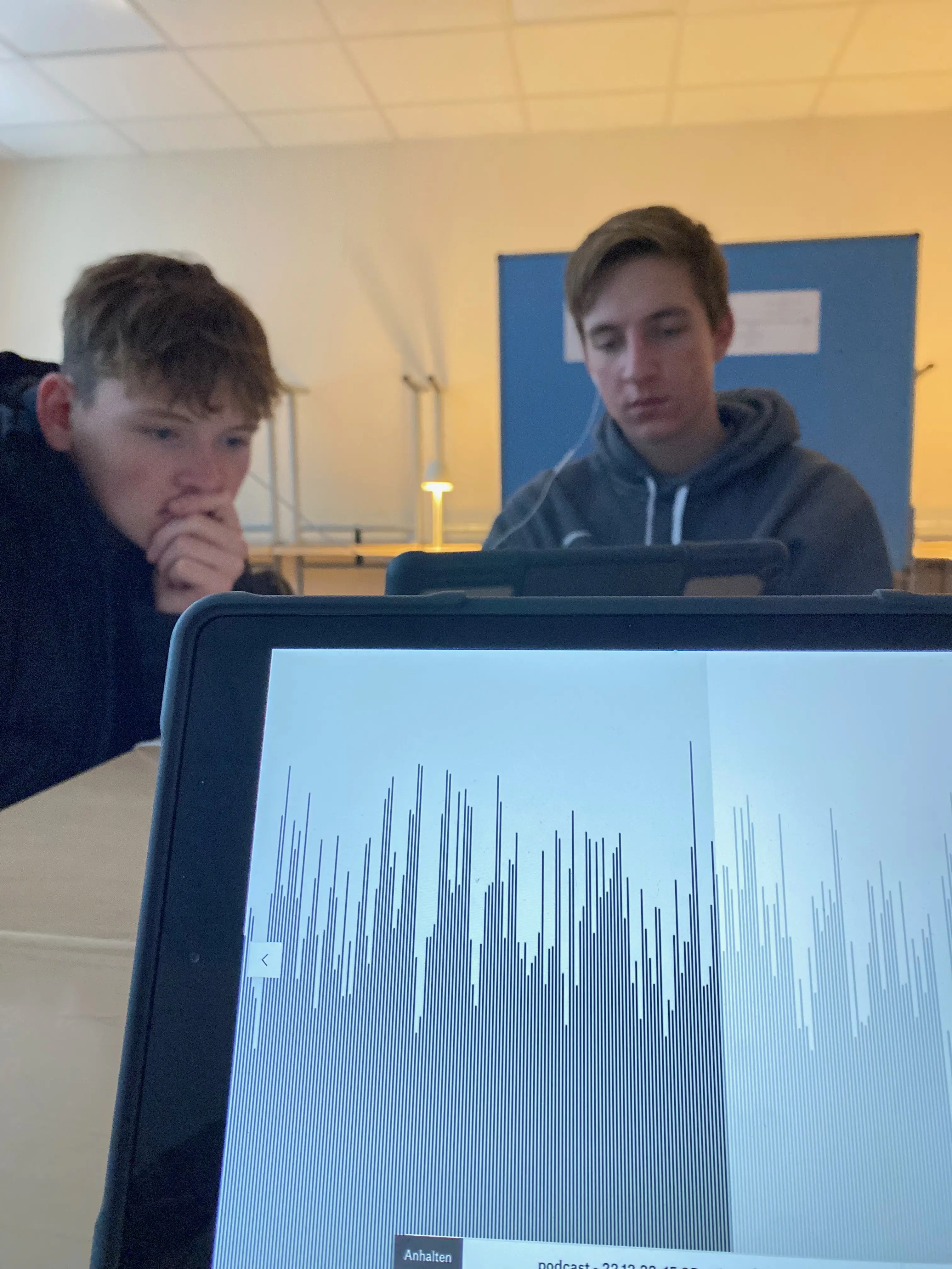 iPad mit Podcast, Schüler mit Kopfhöhrern im Hintergrund